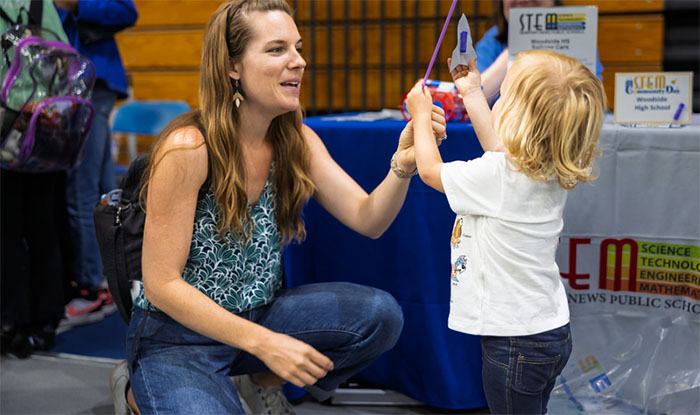 Adult woman interacting with young preschool age child at STEM event
